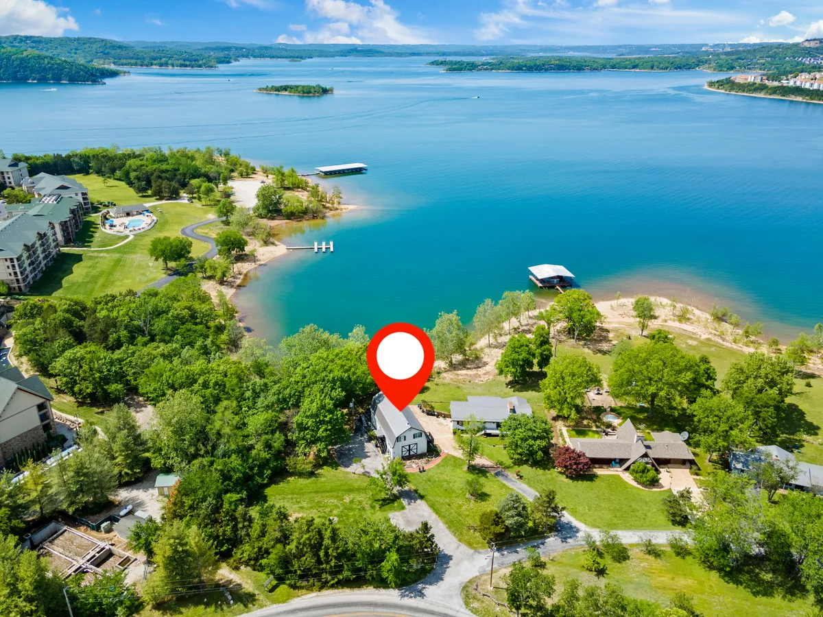 A wide view of a tranquil lake bordered by lush greenery and a charming house, with a boat dock extending over the water. The scene encourages outdoor activities like boating and peaceful walks, and evokes the feeling of being steps away from lakeside adventures.