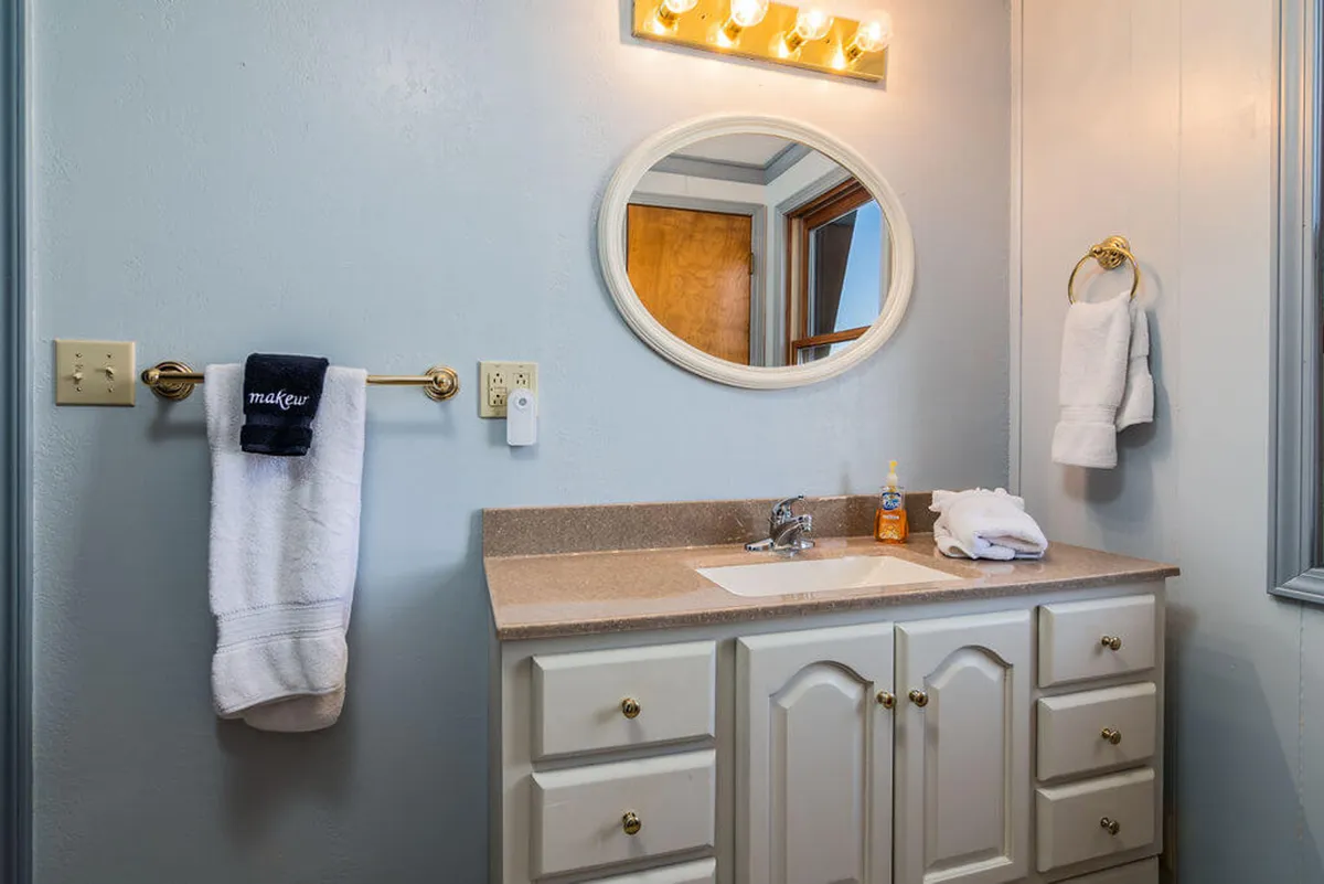 A refreshing bathroom space featuring a well-lit mirror, modern sink and vanity, and neatly arranged towels, evoking a spa-like feel. The décor is simple yet elegant, enhancing the bathroom's calming atmosphere.