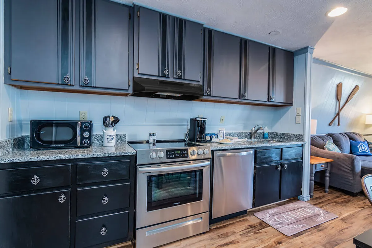This homey kitchen scene features well-organized cabinets, stainless steel appliances, granite countertops, and a comfortable seating area. Decorative oars on the wall add a touch of whimsy and personality. The space looks ready for cooking family meals or hosting special celebrations.